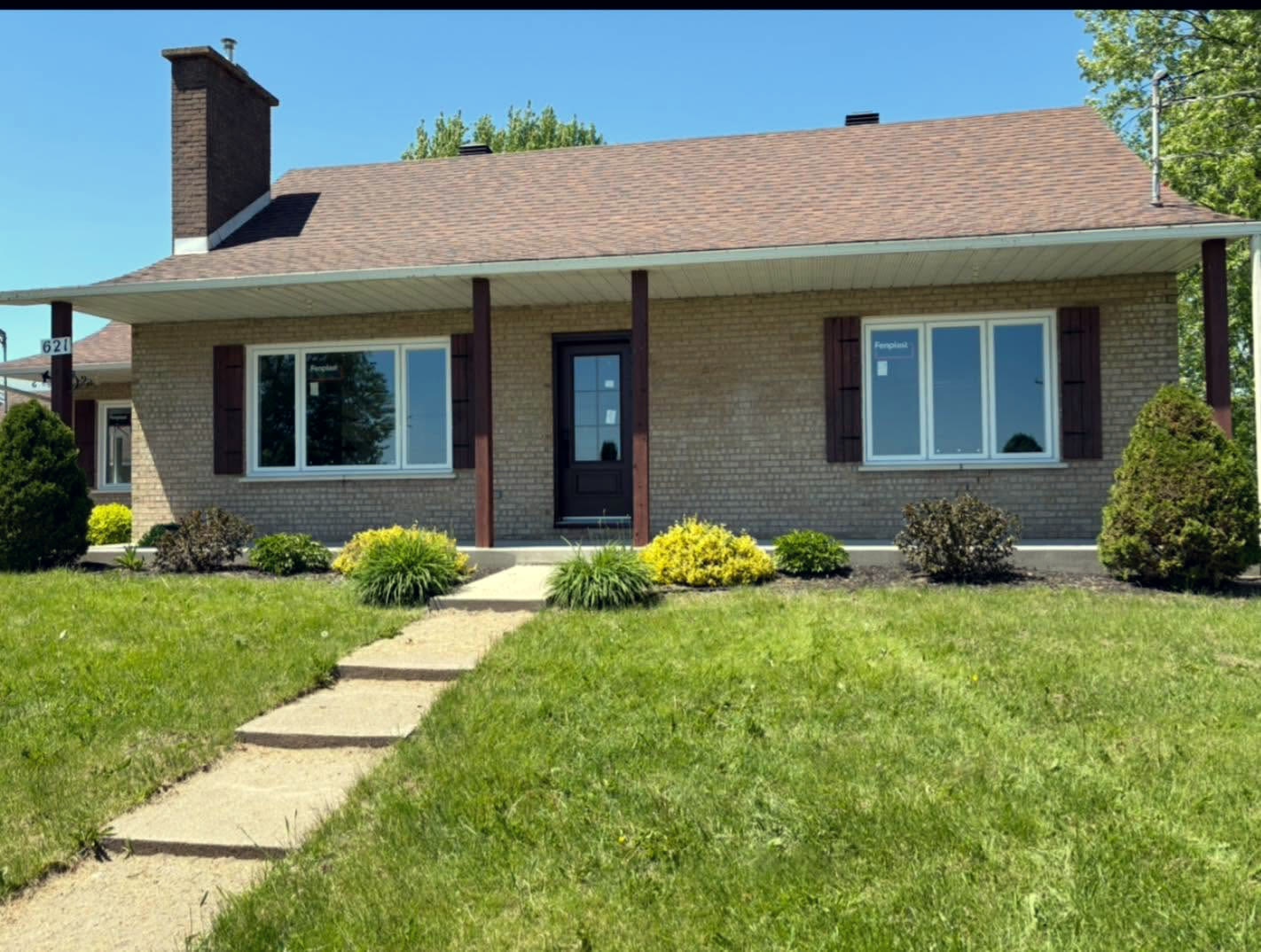 Nouvelles fenêtres installées sur une maison de brique avec allée pavée