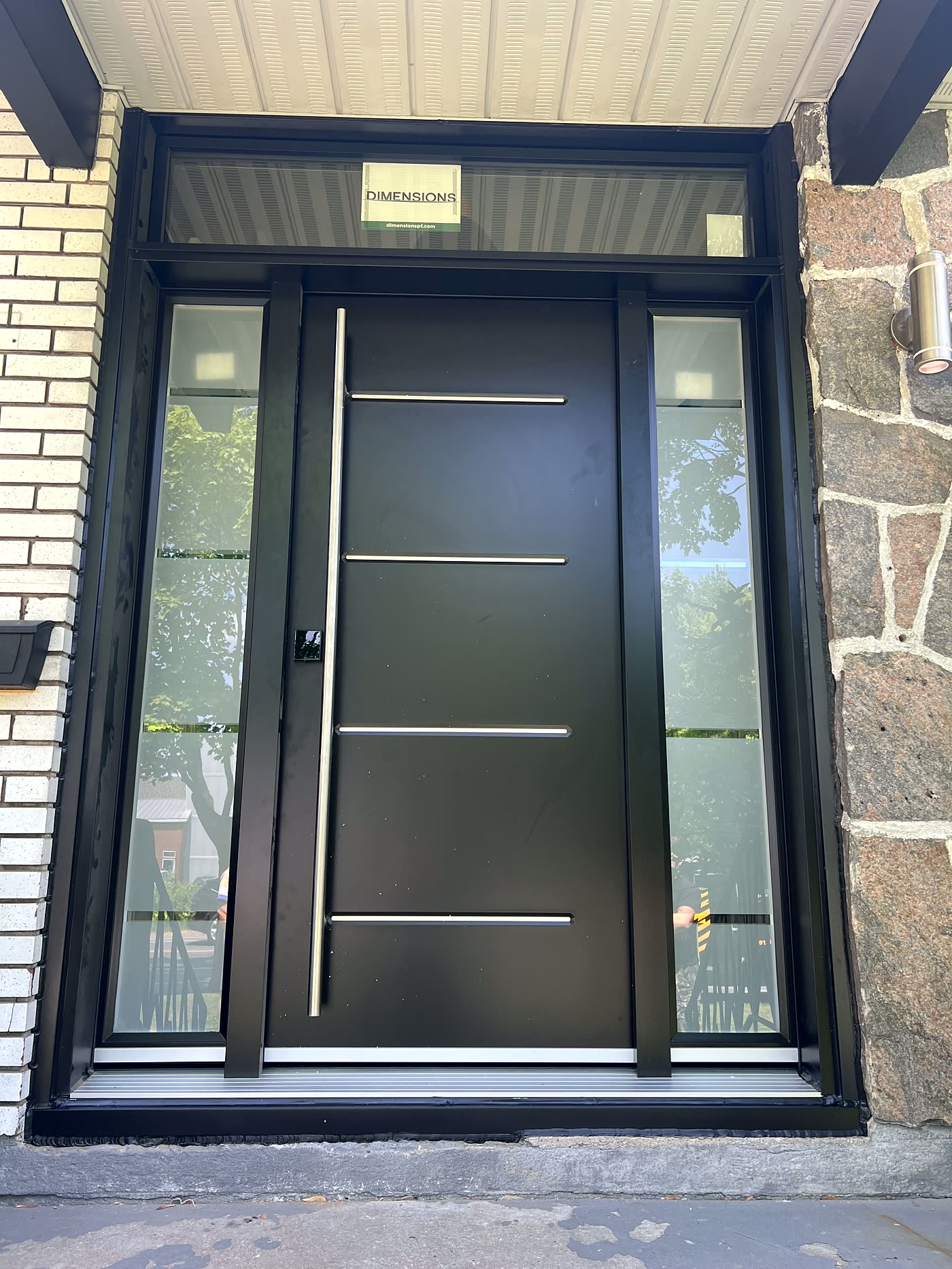 Porte d'entrée moderne noire avec panneaux vitrés latéraux, installée par Cossette & Landry